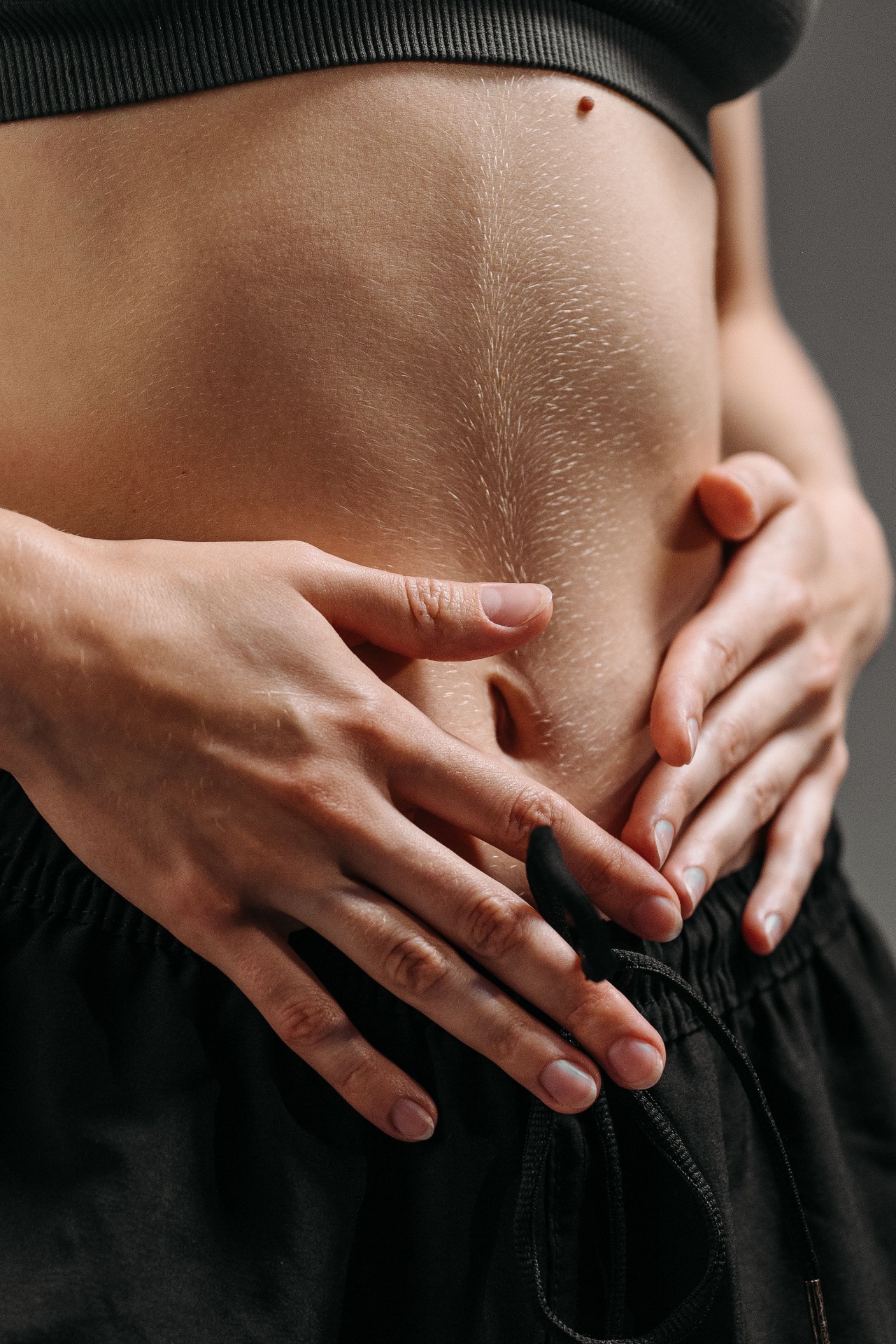 Gros plan de mains posées sur le ventre d'une femme — soutien de la santé intestinale avec la glycine du bouillon d'os