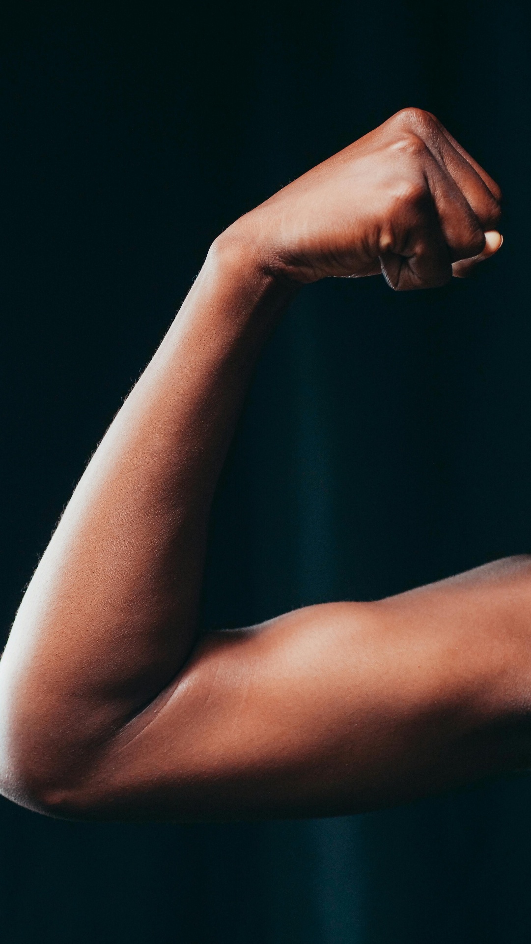 Flexed bicep against a dark background — bone broth for sport, recovery and performance