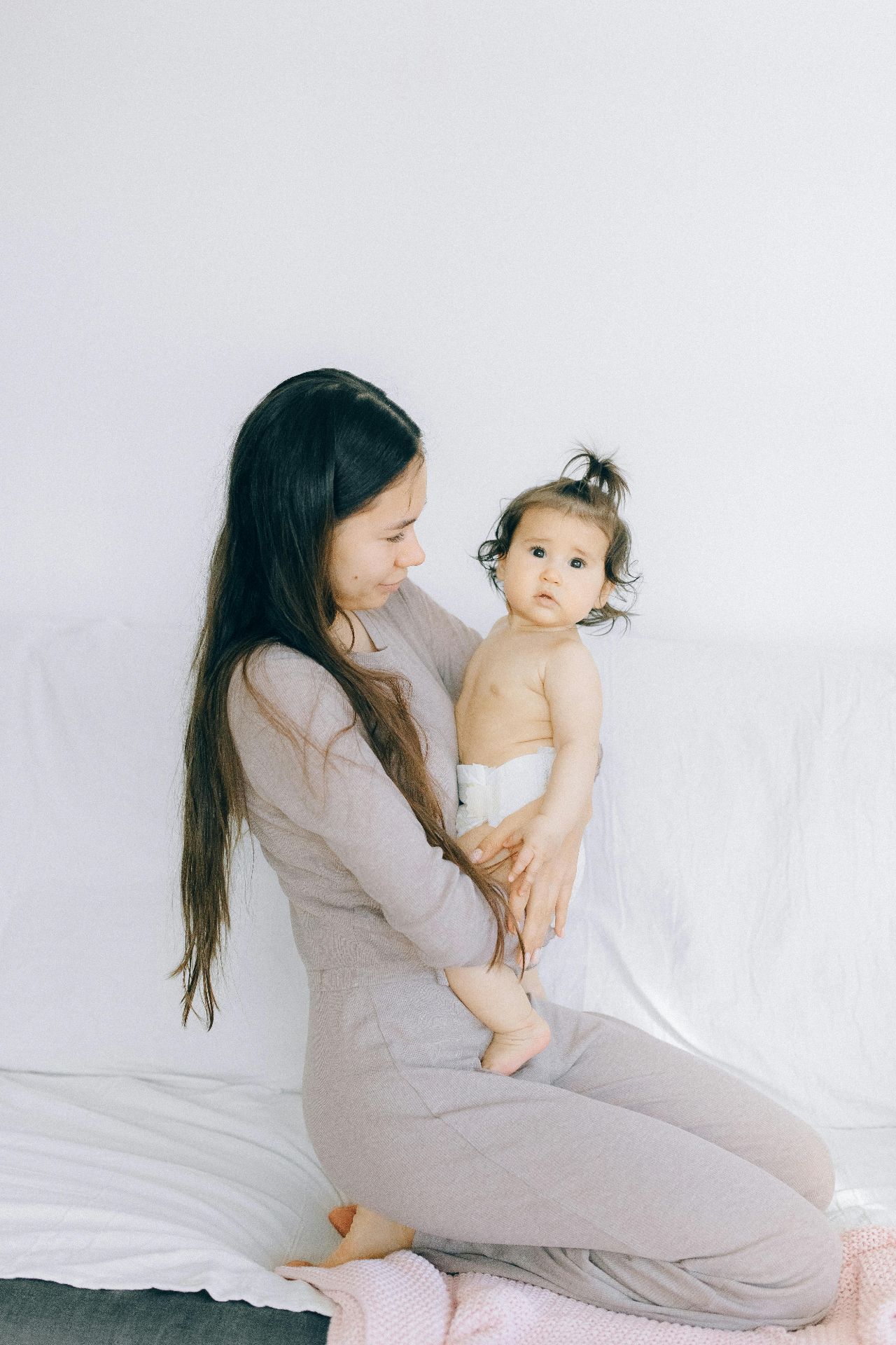 Mother holding her baby on a bright bed with white linens — postpartum recovery and bone broth