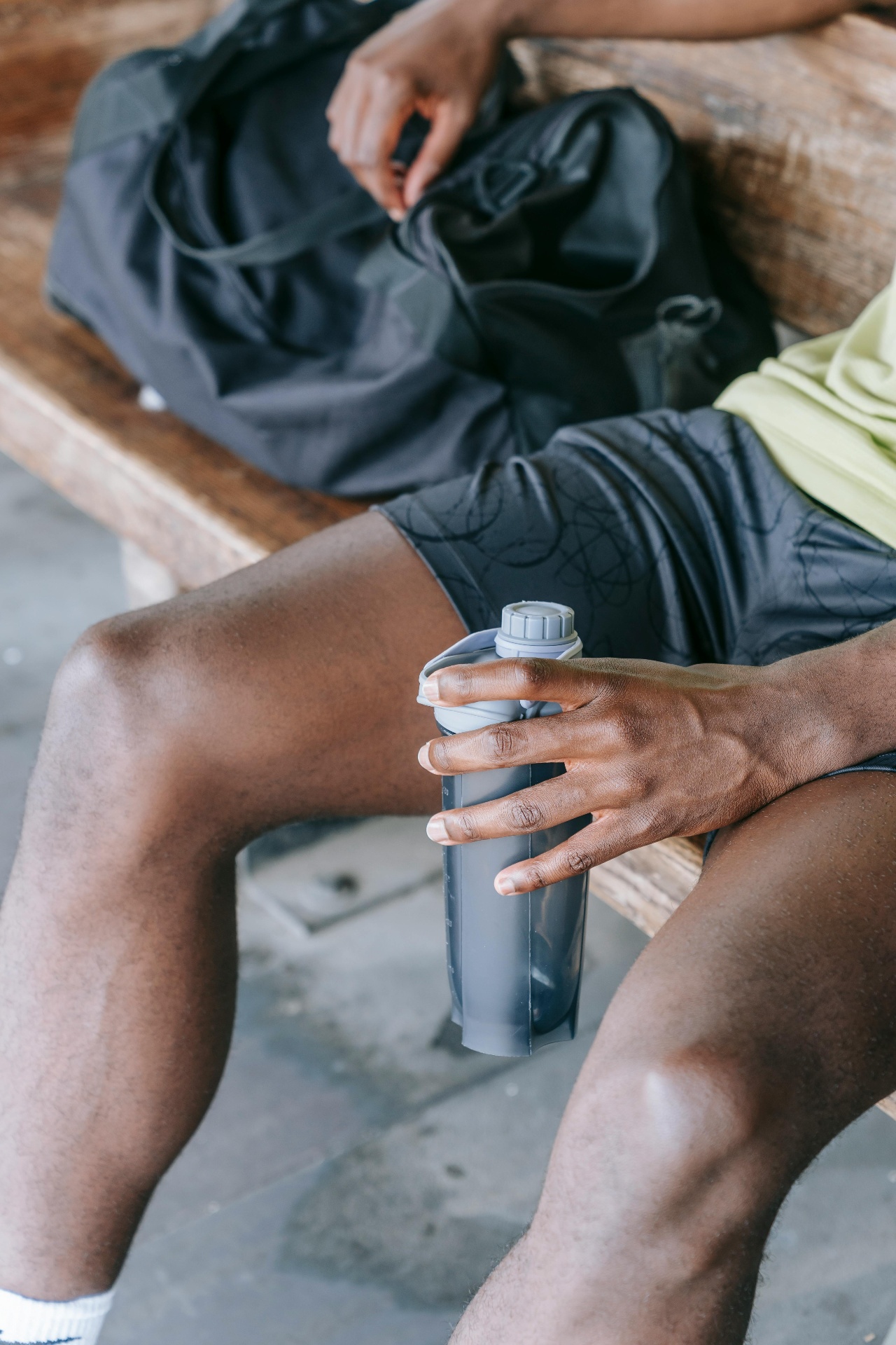 Athlète assis sur un banc tenant un shaker de protéines — protéines de bouillon d'os vs whey