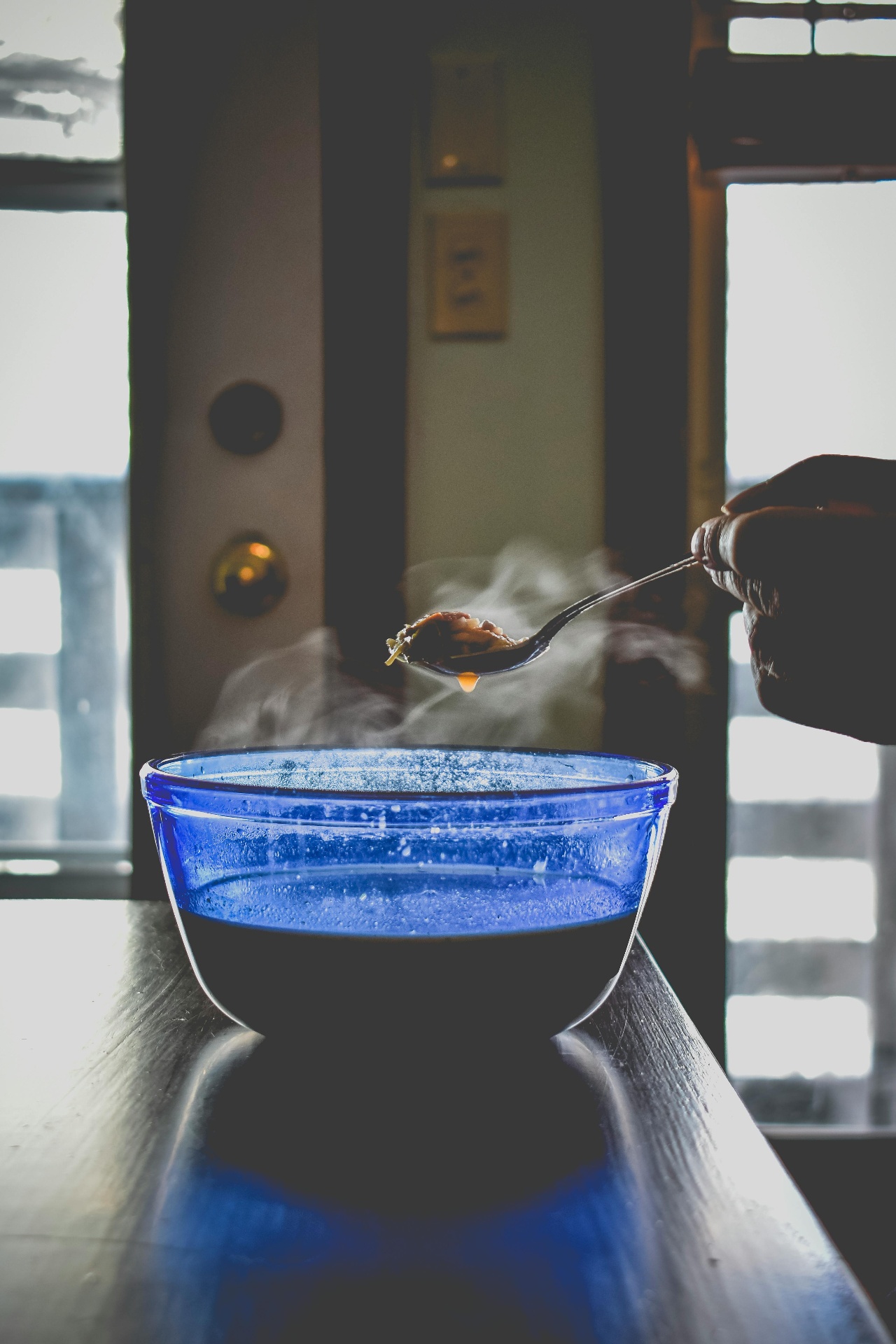 Bol en verre bleu de bouillon d'os fumant avec une cuillère — quelle quantité de bouillon d'os boire par jour